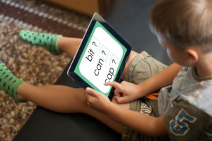 Boy sitting with iPad, using a Google Slides resource to practice CVC to silent e words.