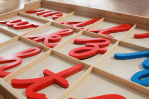 Montessori cursive moveable alphabet made of red and blue wooden letters. 