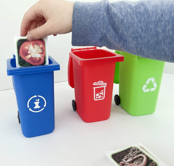 A child sorting pictures of things that can be trash, recycled, or composted into miniature sorting bins.